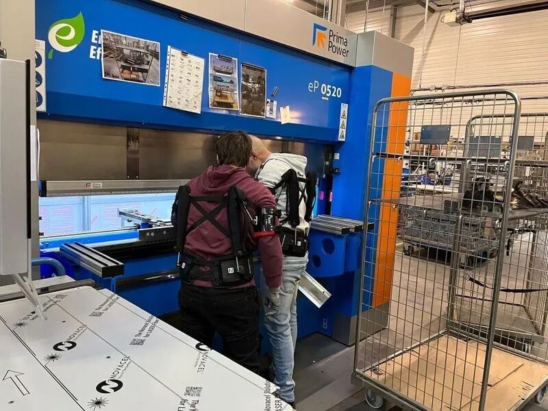 Manutentionnaires dans une usine avec un exosquelette Plum'