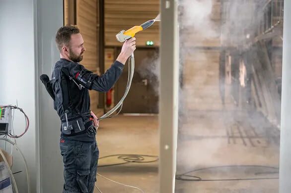 Homme nettoyant une vitre avec son exosquelette HMT